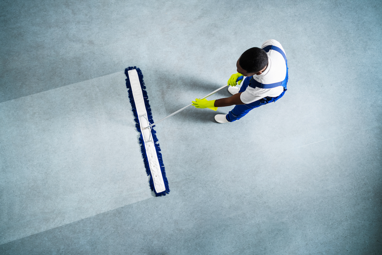 man passing a floor dust mop on commercial office