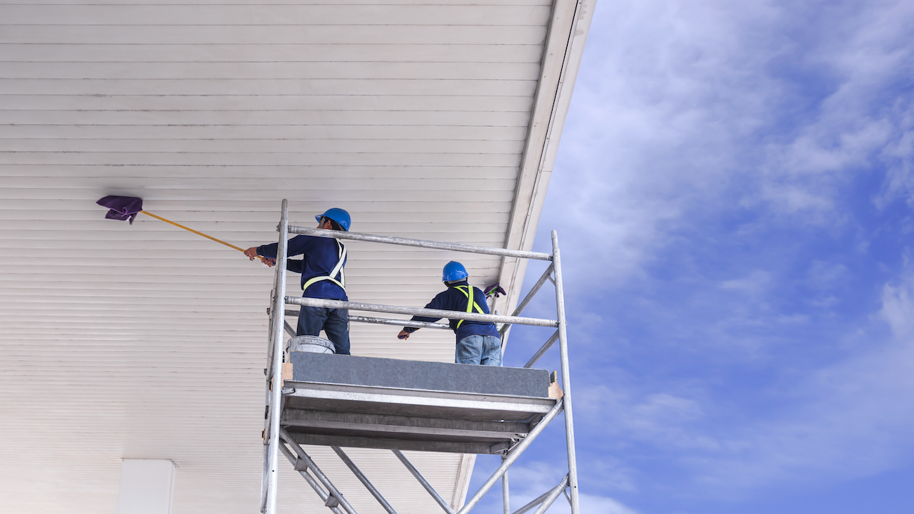 Two men doing high dusting on commercial offices